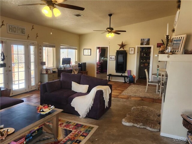 living area featuring lofted ceiling, a healthy amount of sunlight, visible vents, and a ceiling fan