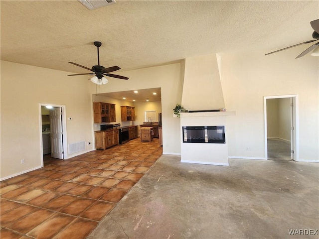 unfurnished living room featuring high vaulted ceiling, a ceiling fan, a textured ceiling, a fireplace, and visible vents