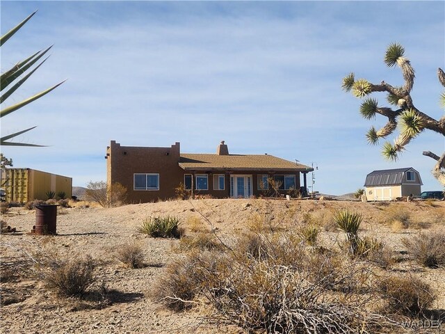 rear view of property featuring an outdoor structure and a shed