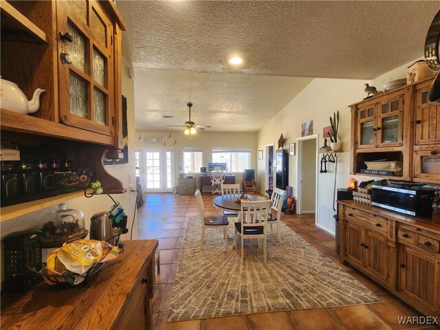 dining space featuring ceiling fan, dark tile patterned floors, and a textured ceiling