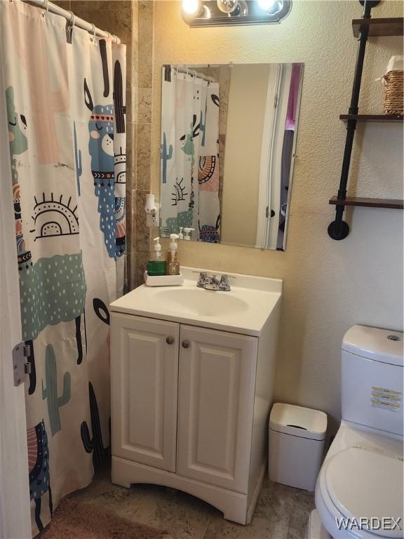 full bathroom with toilet, a textured wall, a shower with shower curtain, and vanity