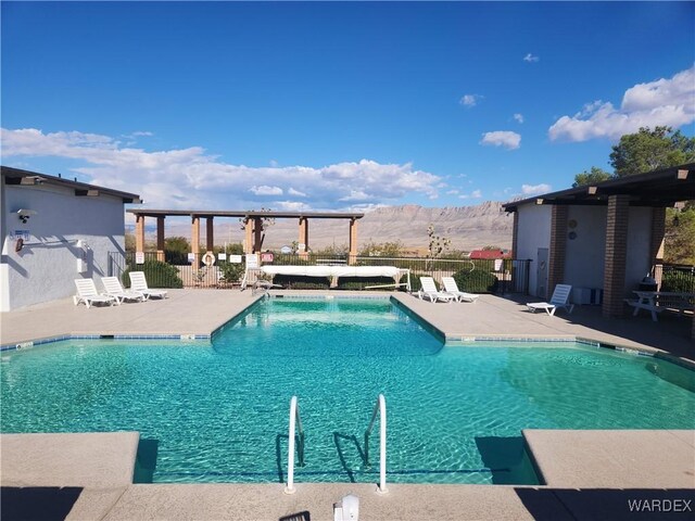 community pool featuring a mountain view, a patio, and fence