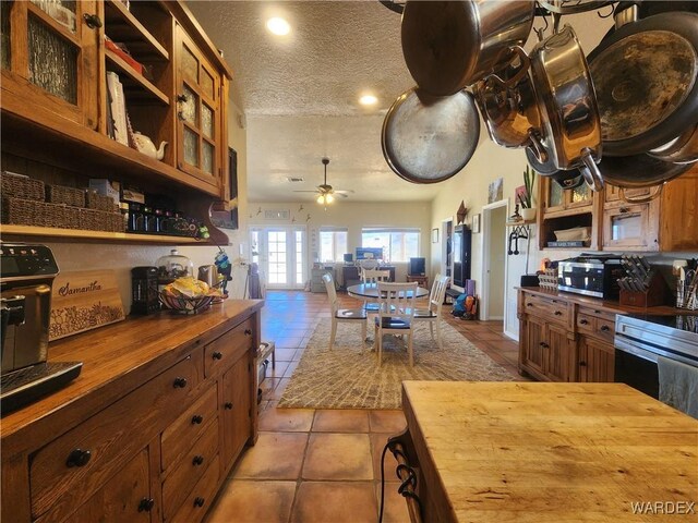 kitchen with light tile patterned floors, ceiling fan, a textured ceiling, open shelves, and wooden counters