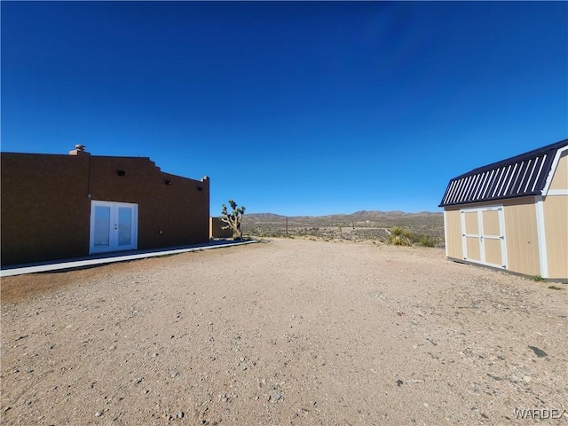 view of yard with a mountain view, an outbuilding, a storage unit, and french doors