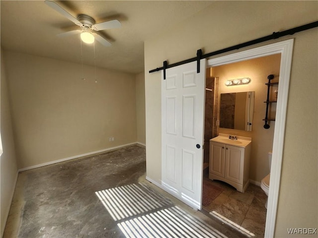 unfurnished bedroom with a barn door, baseboards, and a sink