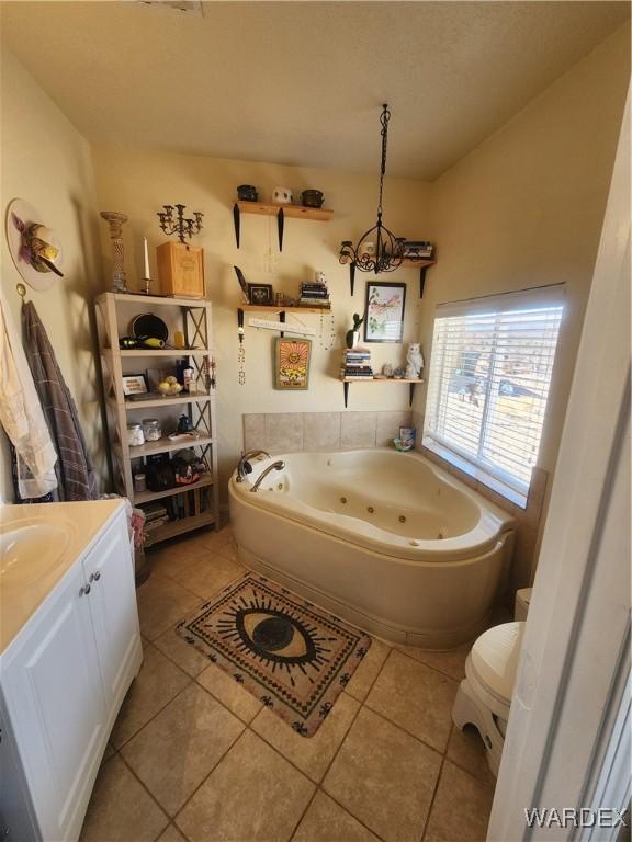 bathroom with toilet, a jetted tub, vanity, and tile patterned floors