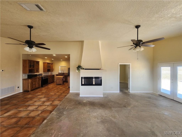 unfurnished living room featuring visible vents, a textured ceiling, and ceiling fan