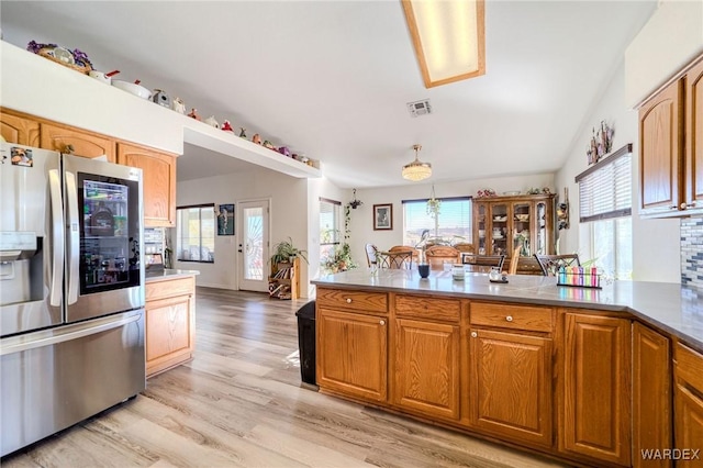 kitchen featuring a peninsula, stainless steel fridge, visible vents, and light wood-style floors