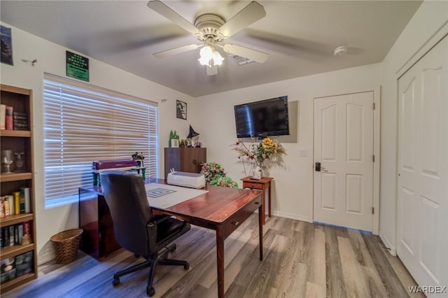 office featuring a ceiling fan, visible vents, baseboards, and wood finished floors