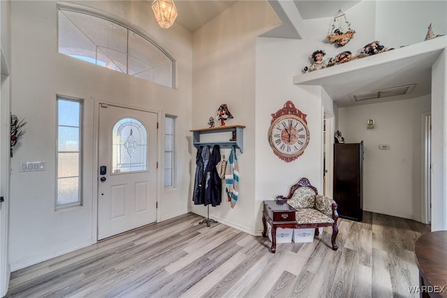 foyer entrance with light wood-type flooring, a high ceiling, and visible vents