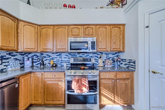 kitchen featuring dark countertops, appliances with stainless steel finishes, brown cabinets, and backsplash