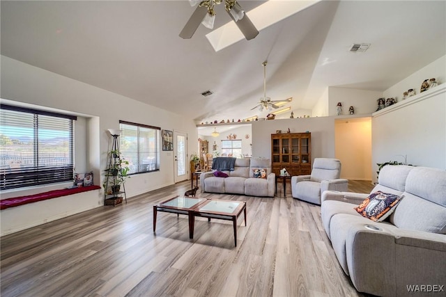 living room featuring light wood finished floors, ceiling fan, visible vents, and high vaulted ceiling