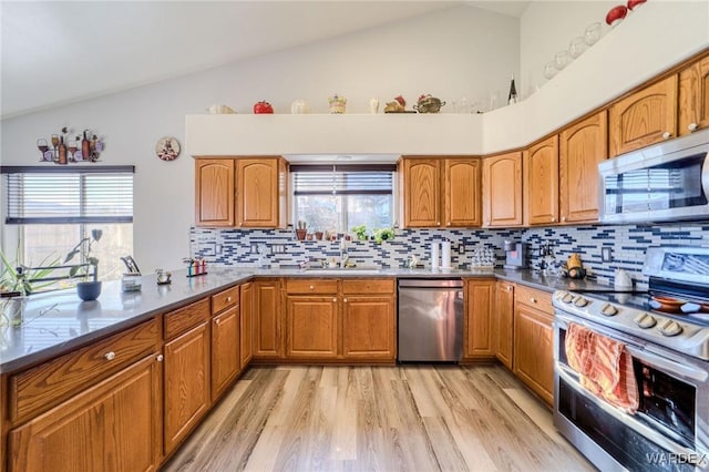 kitchen featuring appliances with stainless steel finishes, brown cabinets, and a sink