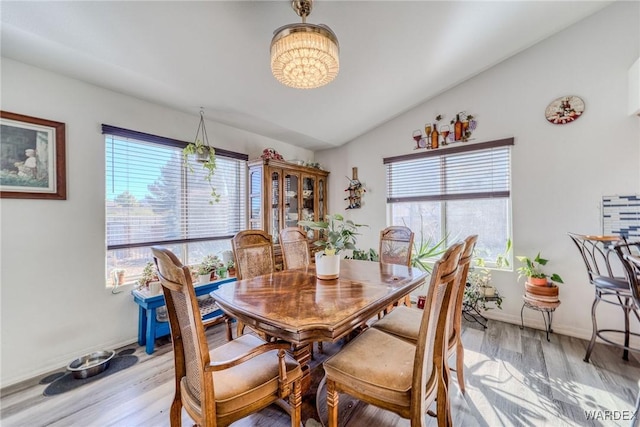 dining space featuring a wealth of natural light, baseboards, lofted ceiling, and light wood finished floors