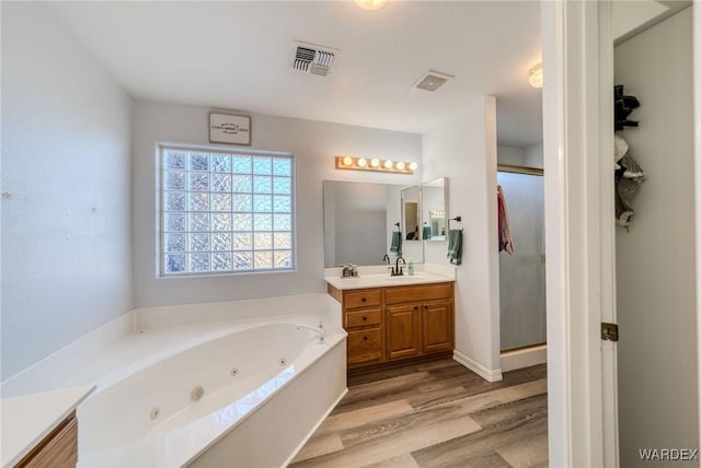 bathroom with wood finished floors, visible vents, vanity, a whirlpool tub, and a stall shower