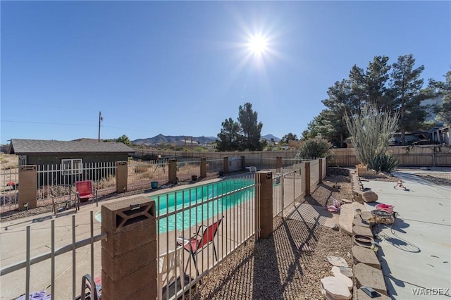 view of pool featuring a mountain view, a patio area, fence, and a fenced in pool