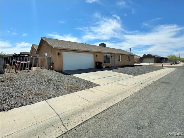 ranch-style home featuring driveway, a garage, fence, and stucco siding