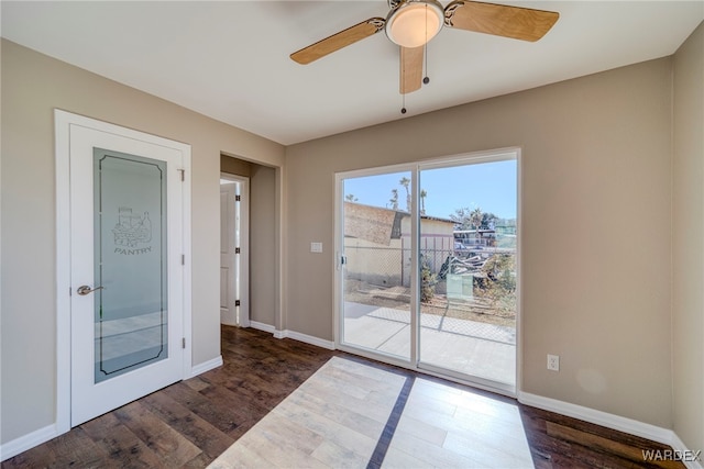 doorway to outside with dark wood-style floors, baseboards, and a ceiling fan