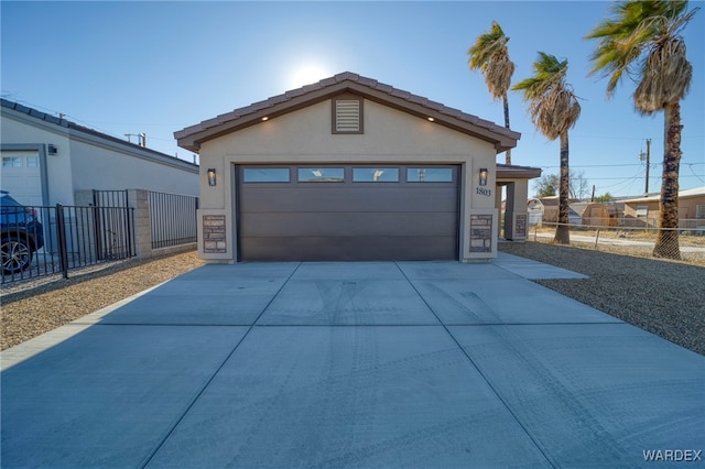 garage with concrete driveway and fence