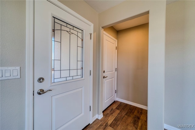 doorway with baseboards and dark wood-type flooring