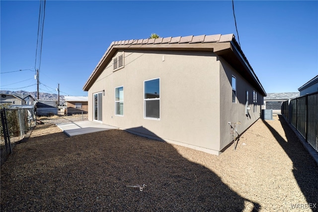 rear view of house featuring central AC, a fenced backyard, and stucco siding