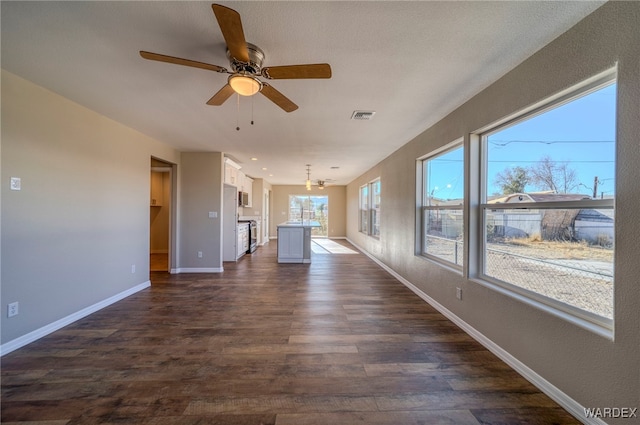 unfurnished living room with baseboards, visible vents, dark wood-type flooring, and ceiling fan with notable chandelier