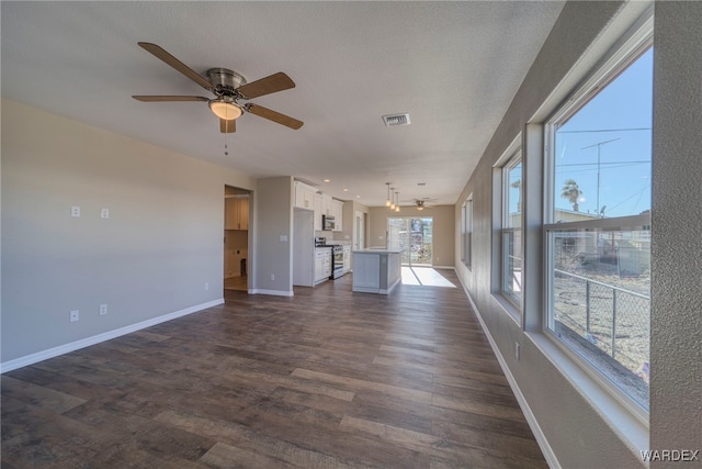 unfurnished living room with dark wood-style floors, visible vents, ceiling fan, a textured ceiling, and baseboards