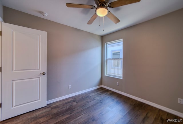 spare room with baseboards, dark wood finished floors, and a ceiling fan