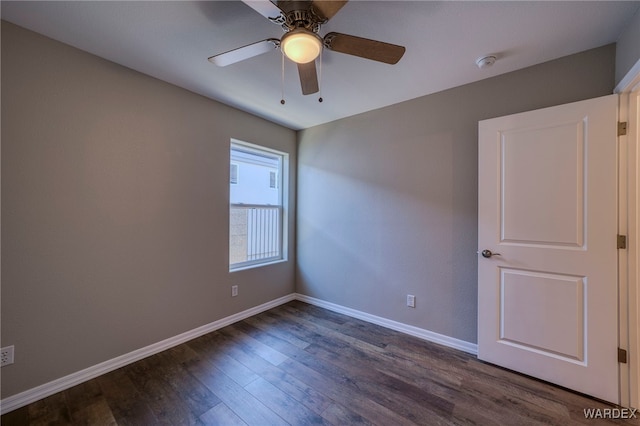 spare room with dark wood-style floors, baseboards, and a ceiling fan