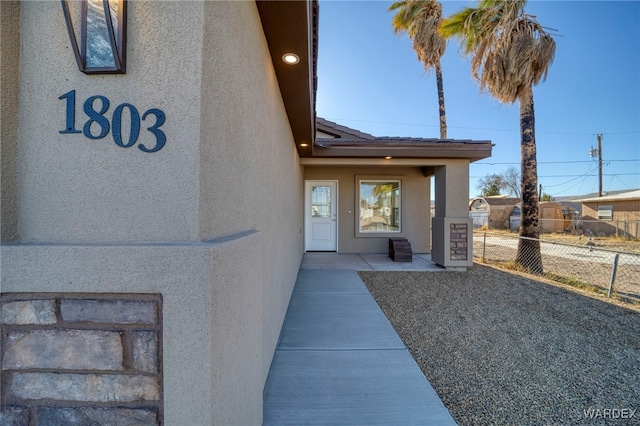 entrance to property with fence and stucco siding