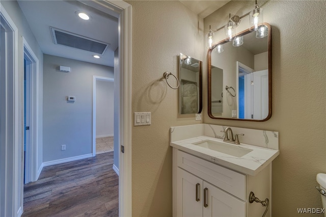 bathroom with visible vents, baseboards, toilet, wood finished floors, and vanity