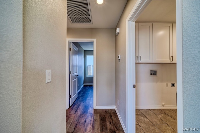 hallway featuring dark wood-style flooring, visible vents, a textured wall, and baseboards