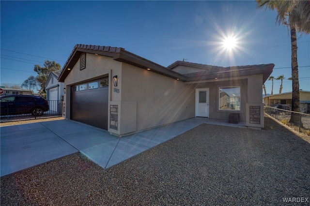 view of front facade featuring driveway, an attached garage, a tile roof, and stucco siding