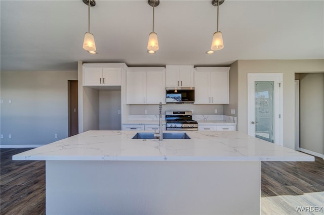 kitchen with light stone counters, stainless steel appliances, white cabinetry, hanging light fixtures, and an island with sink