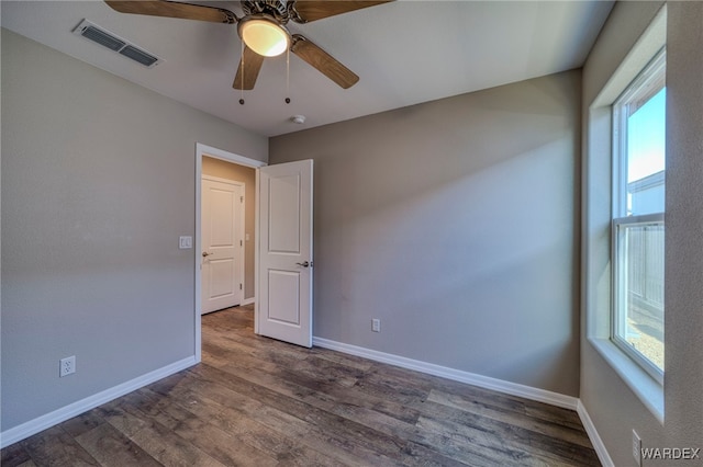 unfurnished room featuring dark wood-style floors, visible vents, ceiling fan, and baseboards