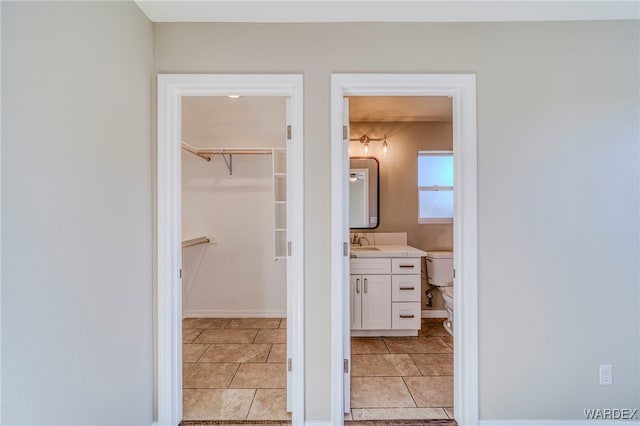 bathroom featuring a walk in closet, tile patterned flooring, vanity, and toilet