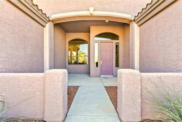 view of exterior entry with a tile roof and stucco siding