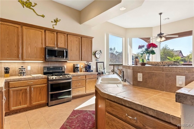 kitchen featuring a sink, visible vents, appliances with stainless steel finishes, tile counters, and decorative backsplash