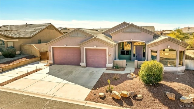 view of front facade featuring a garage, driveway, a tile roof, and stucco siding