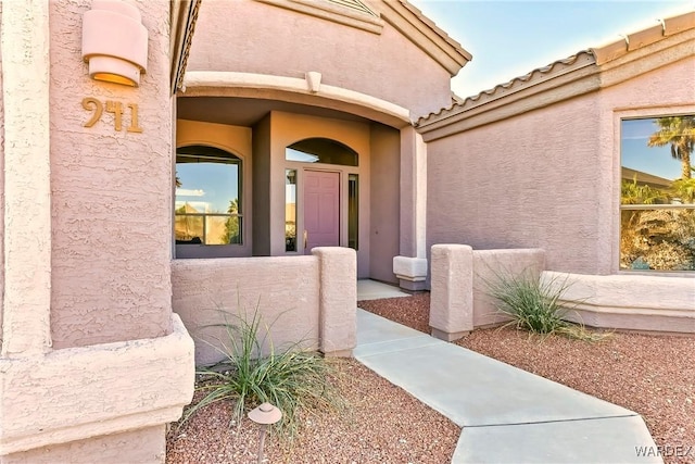 entrance to property with a tiled roof and stucco siding