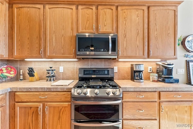 kitchen with appliances with stainless steel finishes, light countertops, and backsplash