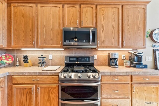 kitchen with appliances with stainless steel finishes, light countertops, and backsplash