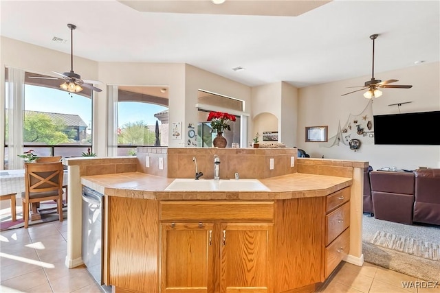 kitchen featuring open floor plan, light countertops, brown cabinetry, and a sink