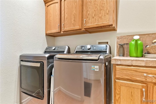 laundry area featuring separate washer and dryer and cabinet space