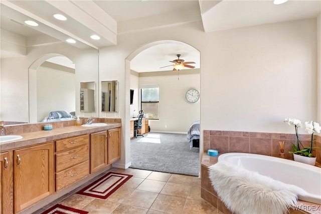 ensuite bathroom with double vanity, ensuite bath, ceiling fan, tile patterned floors, and a sink