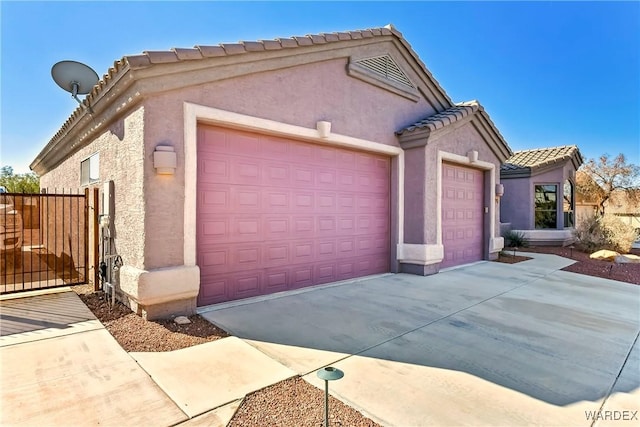 view of front of property with a tiled roof, an attached garage, driveway, and stucco siding