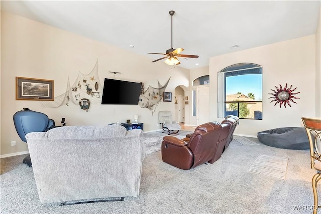 living room with ceiling fan, arched walkways, baseboards, and light colored carpet