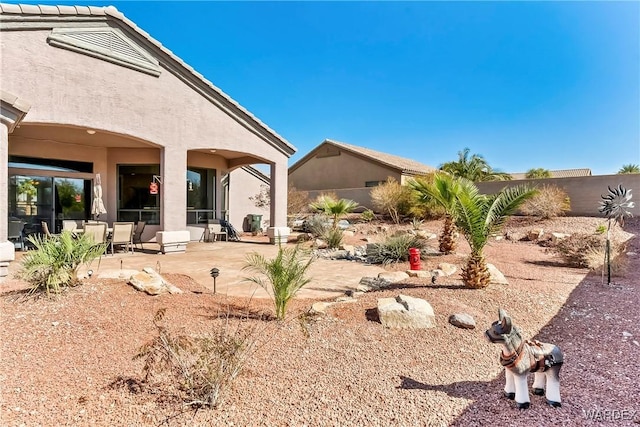 exterior space with a patio area, fence, and stucco siding