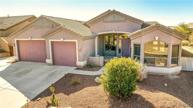 mediterranean / spanish-style house featuring concrete driveway, a tile roof, an attached garage, and stucco siding