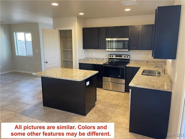 kitchen featuring stainless steel appliances, light stone countertops, a sink, and a kitchen island